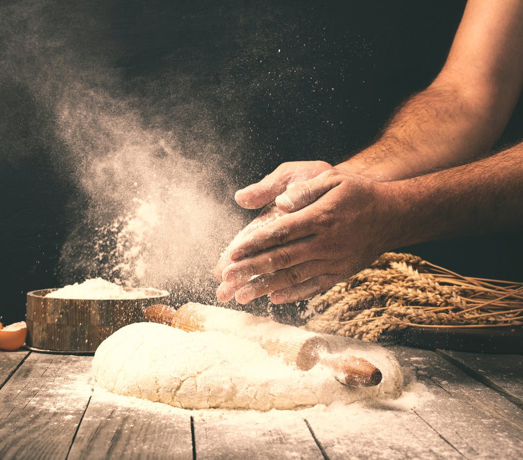 A baker clapping their hands over a pile of dough